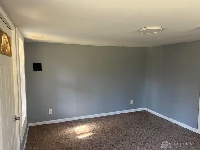 empty room with dark colored carpet and baseboards