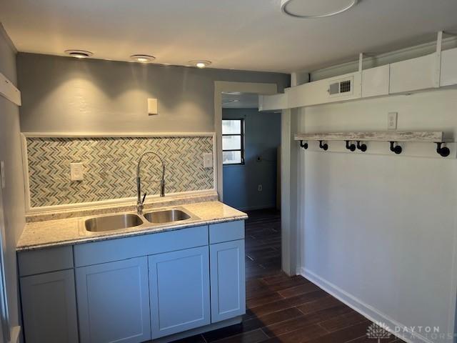 kitchen with a sink, visible vents, baseboards, tasteful backsplash, and dark wood finished floors