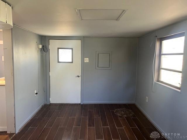 unfurnished room featuring attic access, baseboards, and dark wood-style flooring