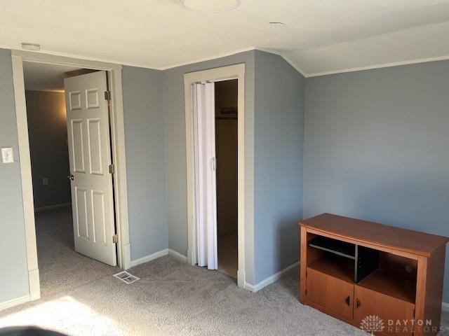 unfurnished bedroom with carpet floors, baseboards, visible vents, and vaulted ceiling