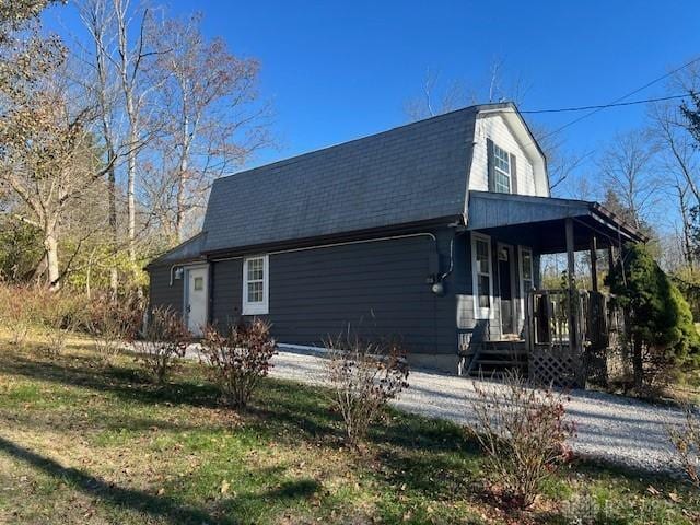 view of property exterior with roof with shingles and a gambrel roof