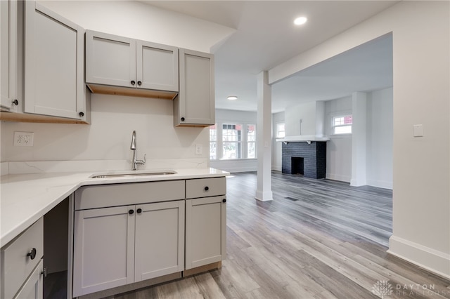 kitchen featuring a fireplace, gray cabinets, a healthy amount of sunlight, and sink