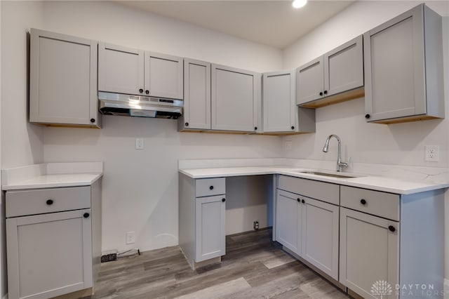 kitchen featuring gray cabinetry, light stone countertops, sink, and light hardwood / wood-style floors