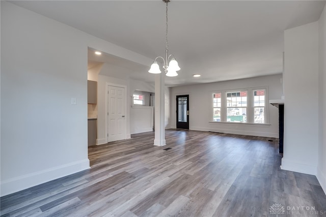 unfurnished living room featuring light wood-type flooring and an inviting chandelier