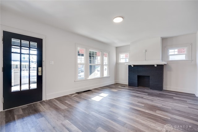 unfurnished living room with light wood-type flooring and a brick fireplace