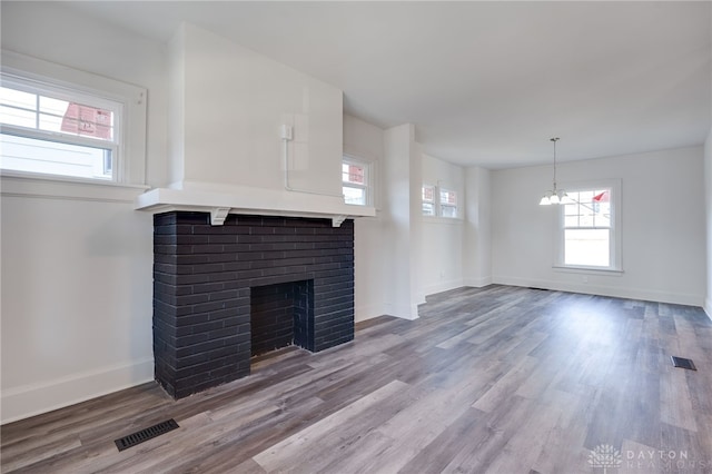 unfurnished living room with a fireplace, hardwood / wood-style floors, and a notable chandelier