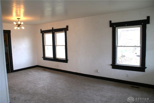 empty room with an inviting chandelier and light carpet