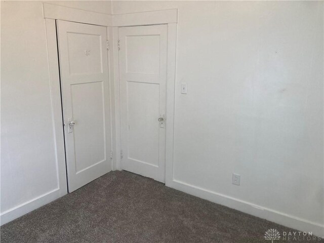 interior space with dark carpet and a closet