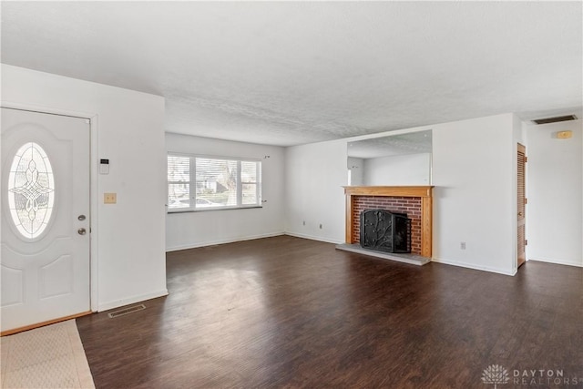 entrance foyer with a textured ceiling, dark hardwood / wood-style flooring, and a brick fireplace