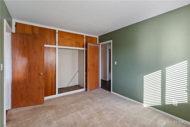 unfurnished bedroom featuring light carpet and a closet