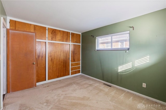 unfurnished bedroom featuring light carpet, a closet, and wood walls