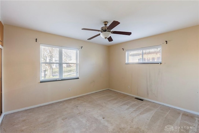 spare room featuring plenty of natural light, ceiling fan, and light colored carpet