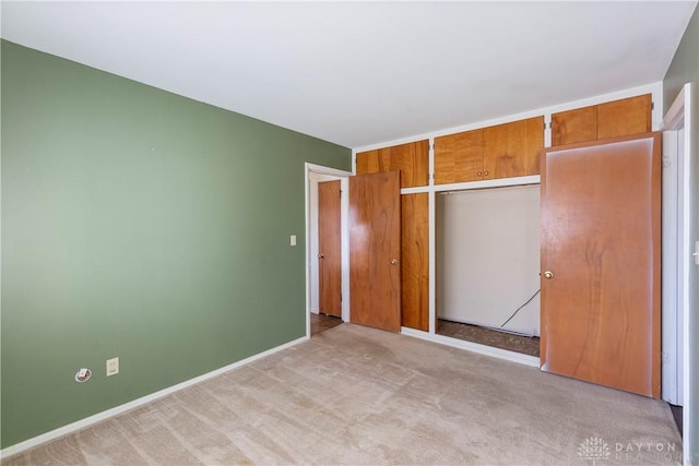 unfurnished bedroom featuring light colored carpet and a closet