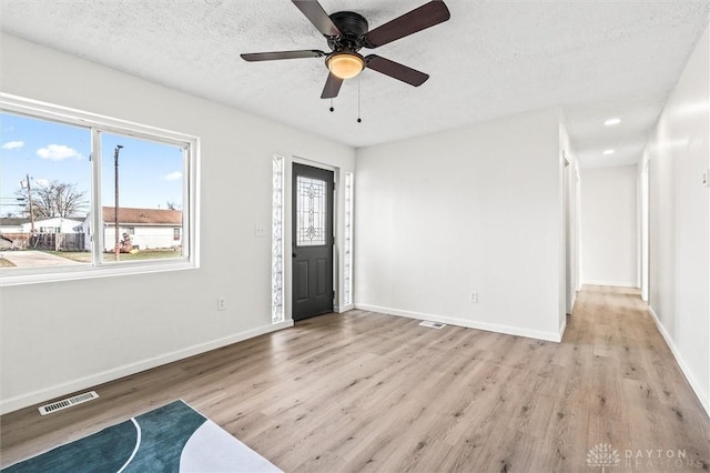 entryway with a textured ceiling, light hardwood / wood-style floors, and ceiling fan