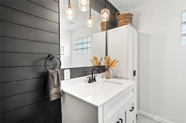 bathroom featuring baseboards, visible vents, a textured ceiling, and vanity