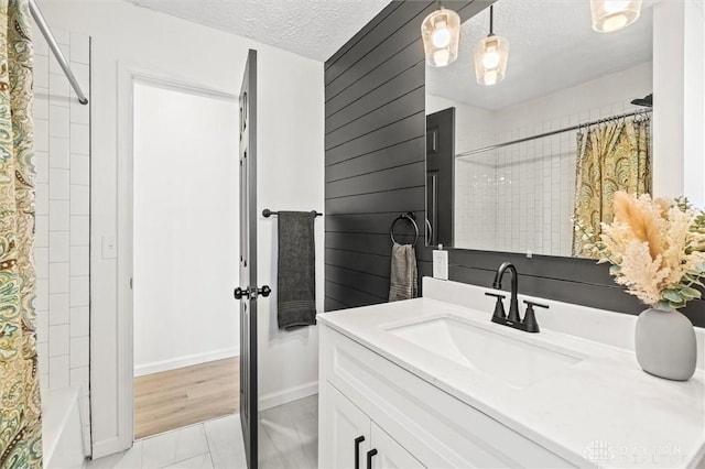 bathroom with shower / bathtub combination with curtain, a textured ceiling, and vanity