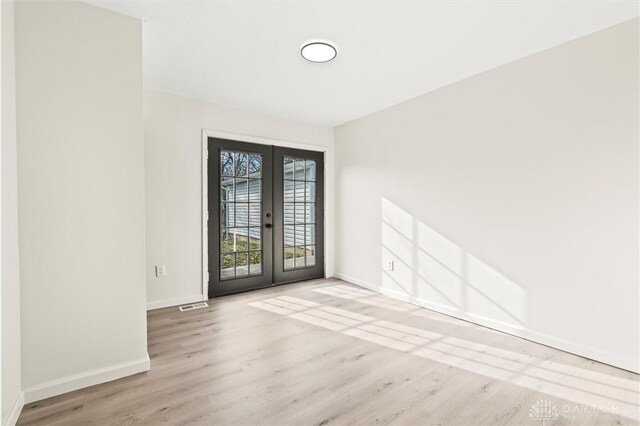 unfurnished room with light hardwood / wood-style floors and french doors