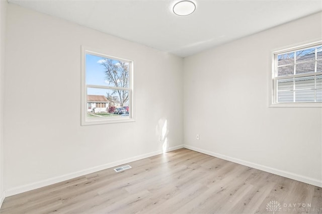 empty room with light wood-style floors, baseboards, and visible vents