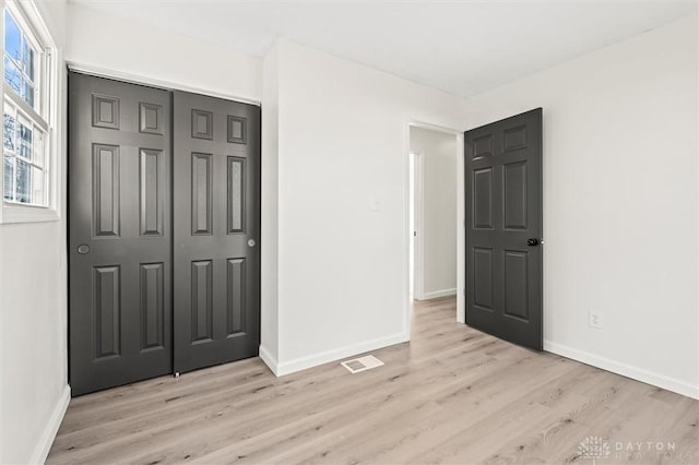 unfurnished bedroom with light wood-style flooring, multiple windows, and visible vents