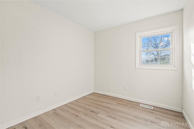 unfurnished room with visible vents, light wood-style flooring, and baseboards