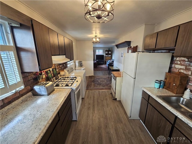 kitchen featuring white appliances, dark wood-type flooring, sink, decorative light fixtures, and a chandelier