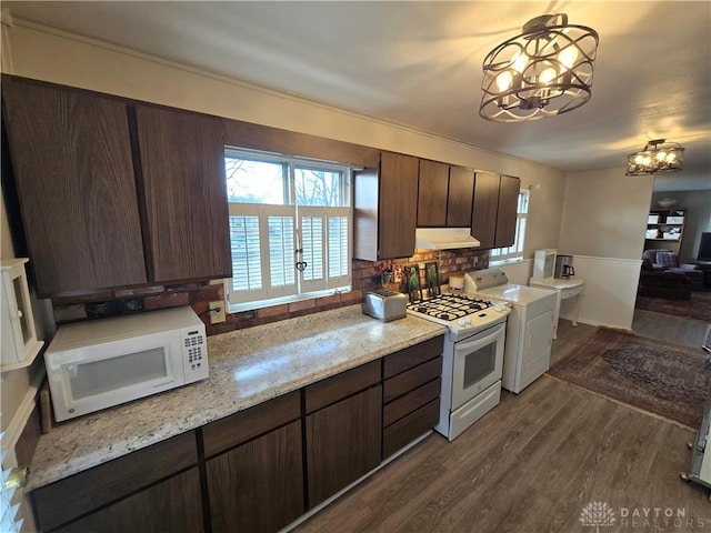 kitchen with dark brown cabinets, white appliances, dark wood-type flooring, an inviting chandelier, and washer / dryer