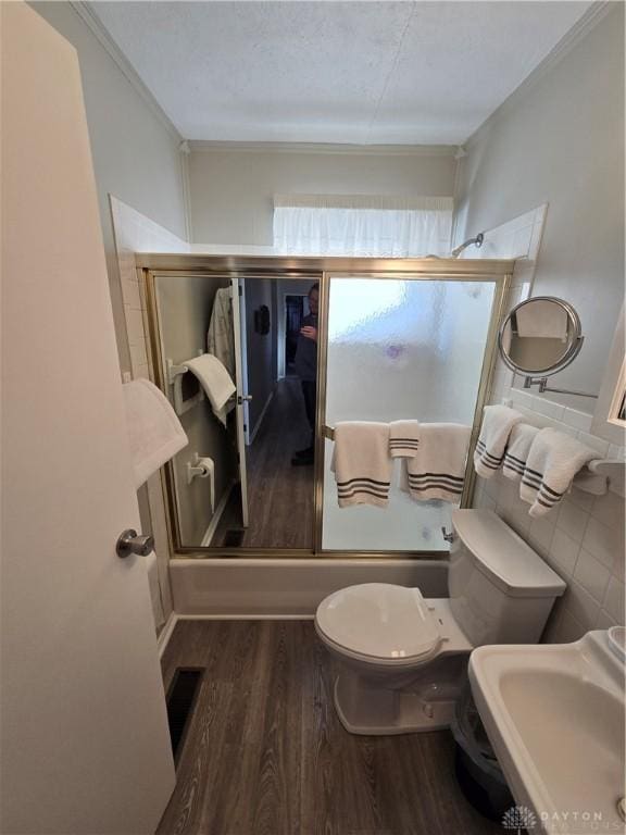 full bathroom featuring toilet, hardwood / wood-style floors, enclosed tub / shower combo, and sink