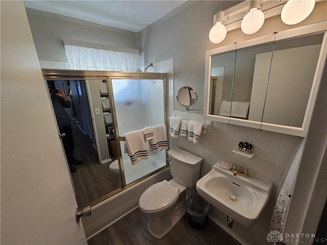 full bathroom featuring tasteful backsplash, sink, shower / bath combination with glass door, hardwood / wood-style flooring, and toilet