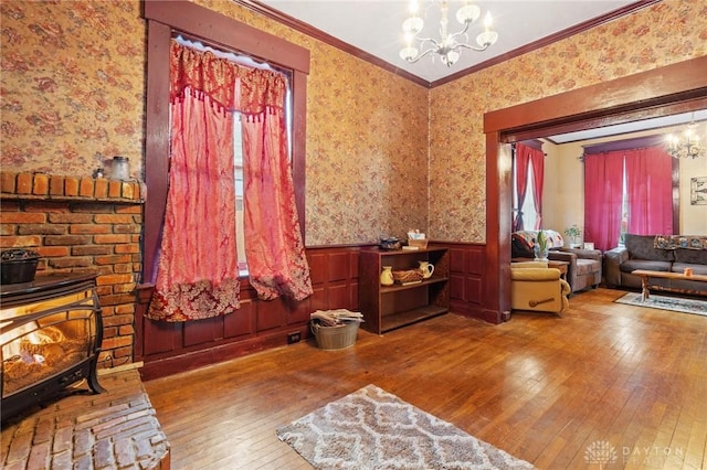 living area featuring ornamental molding, a wood stove, hardwood / wood-style floors, and a chandelier