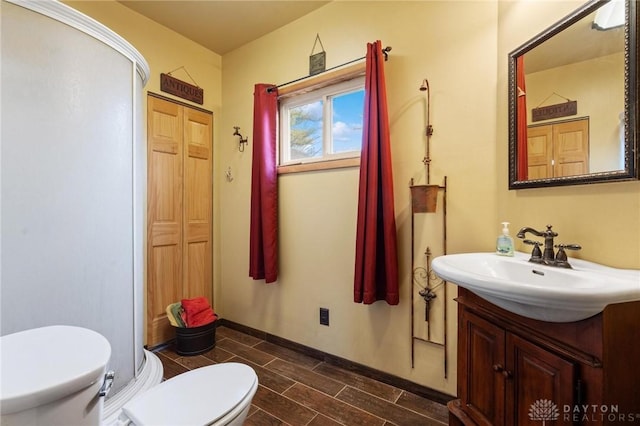 bathroom with a shower with door, vanity, and toilet