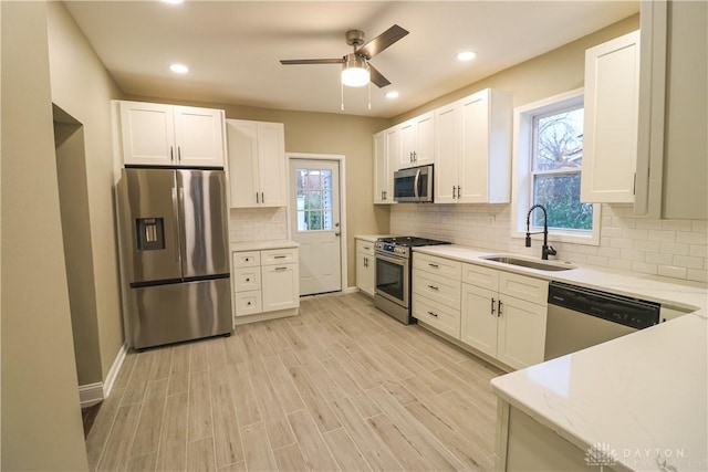 kitchen with a wealth of natural light, white cabinetry, sink, and stainless steel appliances