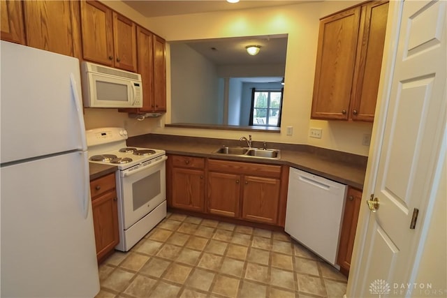 kitchen featuring dark countertops, white appliances, brown cabinets, and a sink