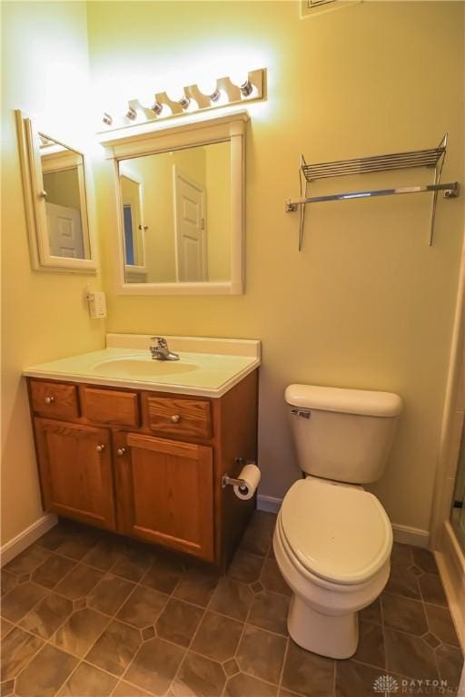 bathroom with toilet, baseboards, vanity, and tile patterned floors