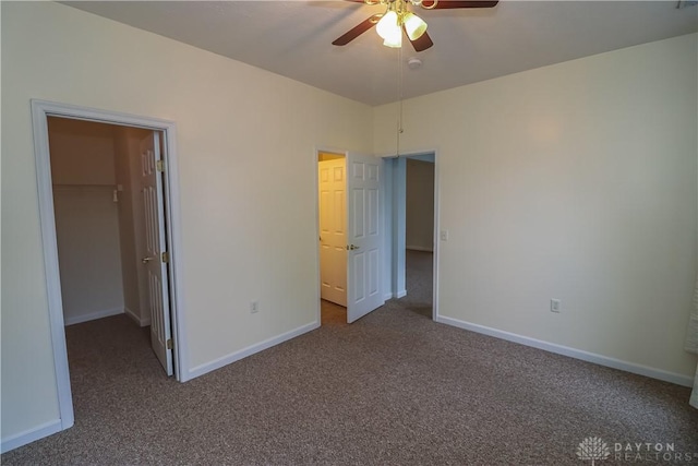 unfurnished bedroom featuring carpet flooring, a walk in closet, a closet, and ceiling fan