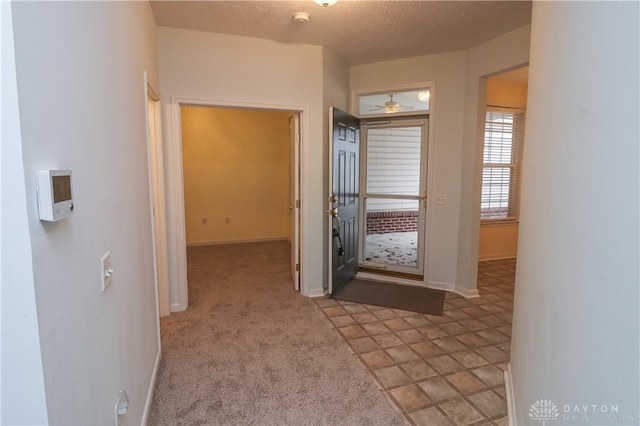 corridor featuring a textured ceiling, carpet floors, and baseboards