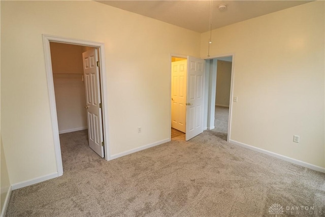 unfurnished bedroom featuring a spacious closet, carpet, and baseboards