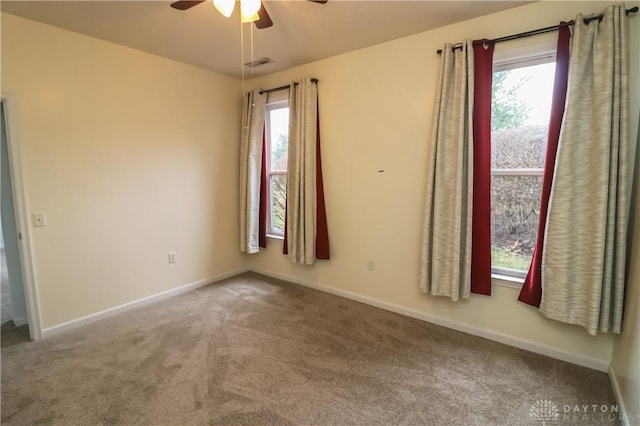 spare room featuring a healthy amount of sunlight, carpet, visible vents, and baseboards