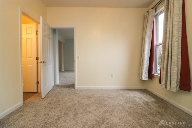 empty room featuring carpet and baseboards