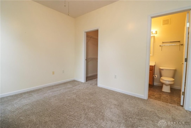 unfurnished bedroom with carpet floors, baseboards, and a walk in closet