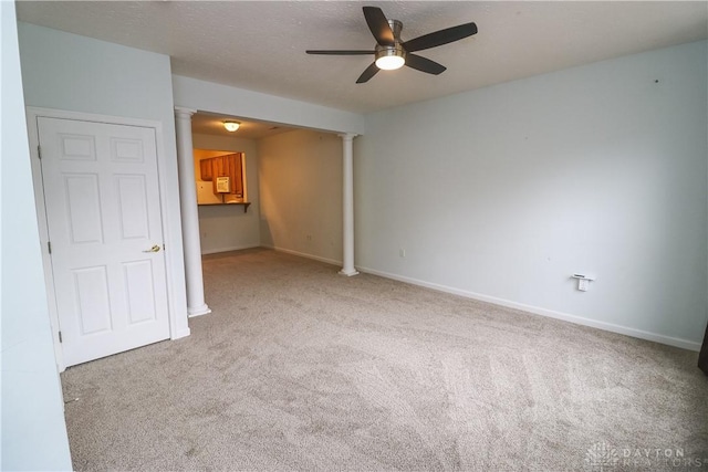 carpeted spare room with ceiling fan, a textured ceiling, decorative columns, and baseboards