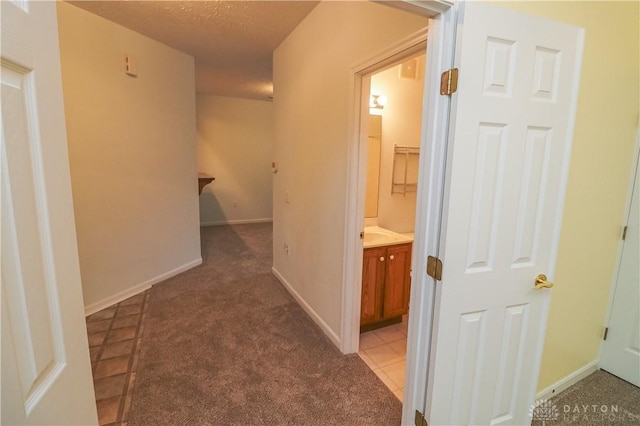 hall with light tile patterned floors, visible vents, light carpet, a textured ceiling, and baseboards