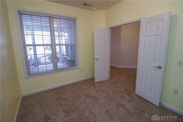 unfurnished bedroom featuring carpet floors, visible vents, and baseboards