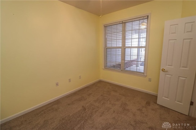 carpeted spare room featuring baseboards