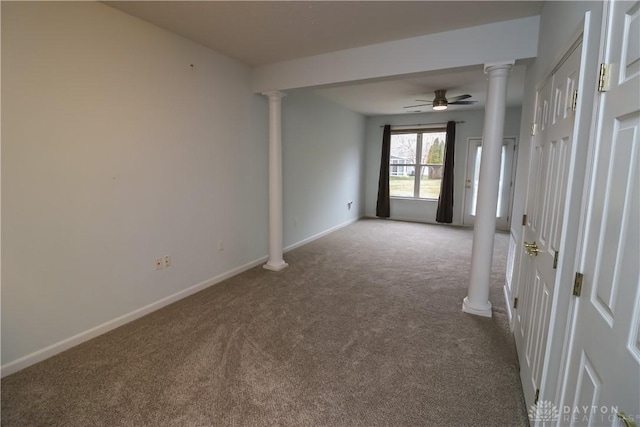 empty room featuring carpet, decorative columns, and baseboards