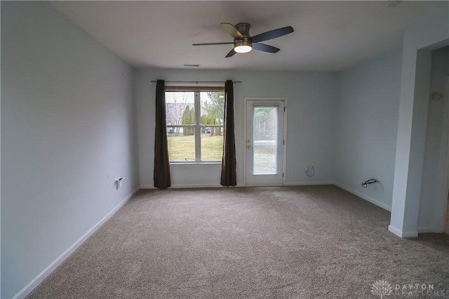 carpeted empty room with ceiling fan, visible vents, and baseboards