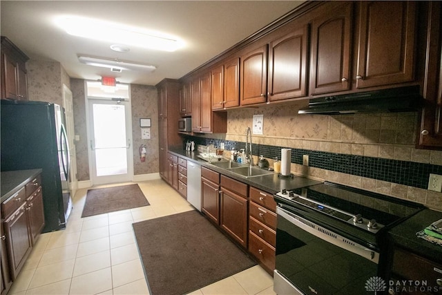 kitchen featuring appliances with stainless steel finishes, dark countertops, a sink, and under cabinet range hood