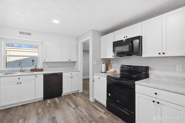 kitchen featuring black appliances, light hardwood / wood-style floors, white cabinets, and sink