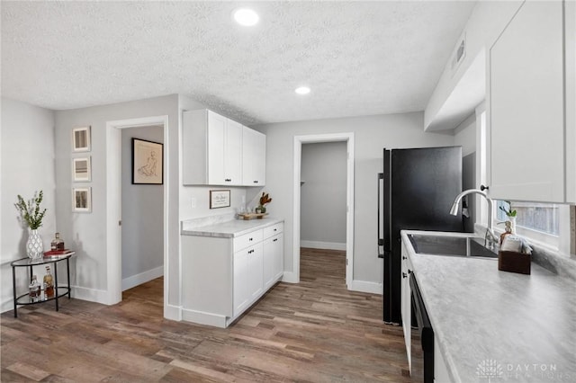 kitchen featuring hardwood / wood-style floors, white cabinets, stainless steel dishwasher, and a textured ceiling