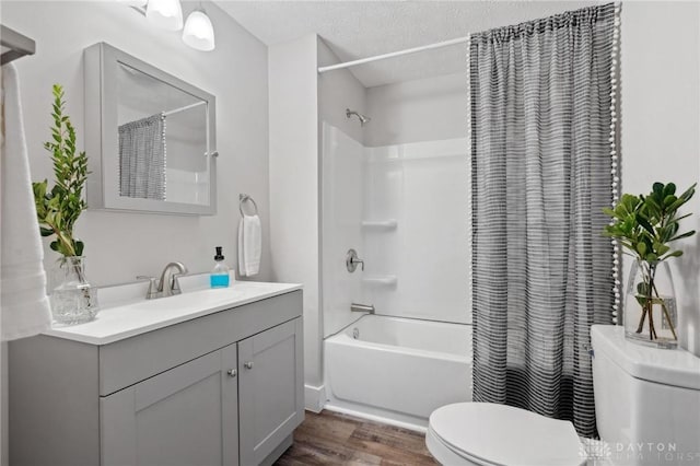 full bathroom featuring hardwood / wood-style floors, vanity, toilet, shower / bath combo with shower curtain, and a textured ceiling