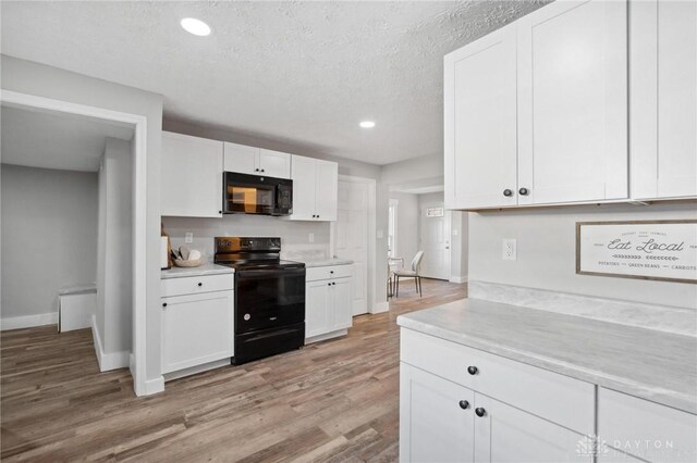 32 W Main St, Phillipsburg, OH 45354 - kitchen with black appliances, light countertops, white cabinets, light wood finished floors, and baseboards